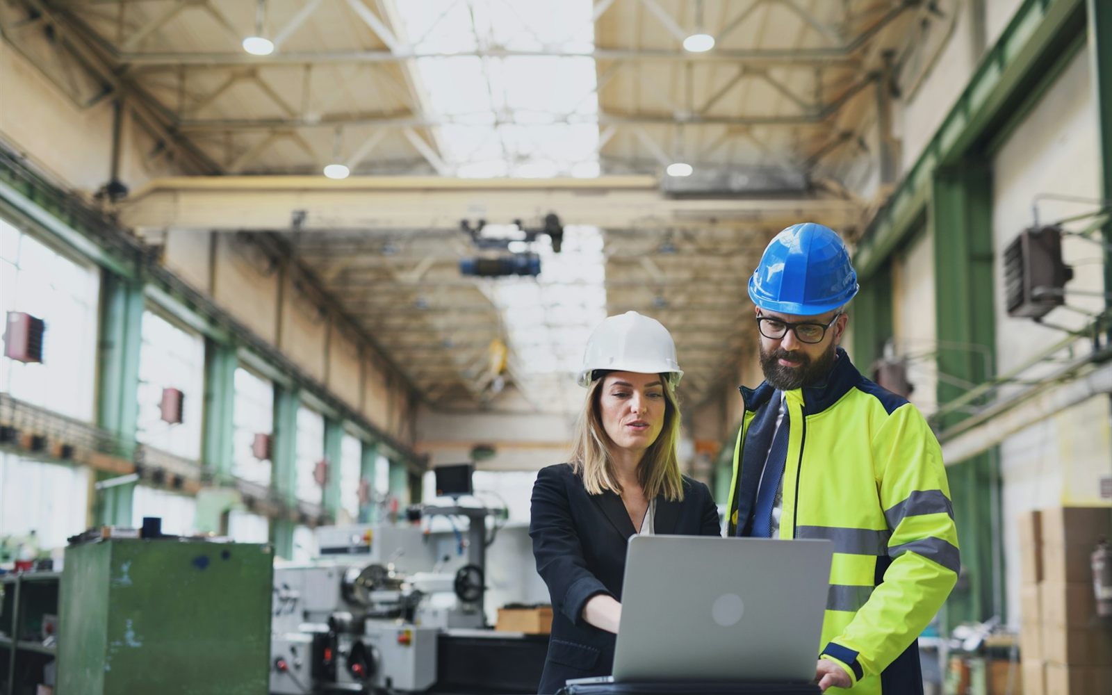Ingeniera y técnico revisando especificaciones en una laptop dentro de una planta industrial