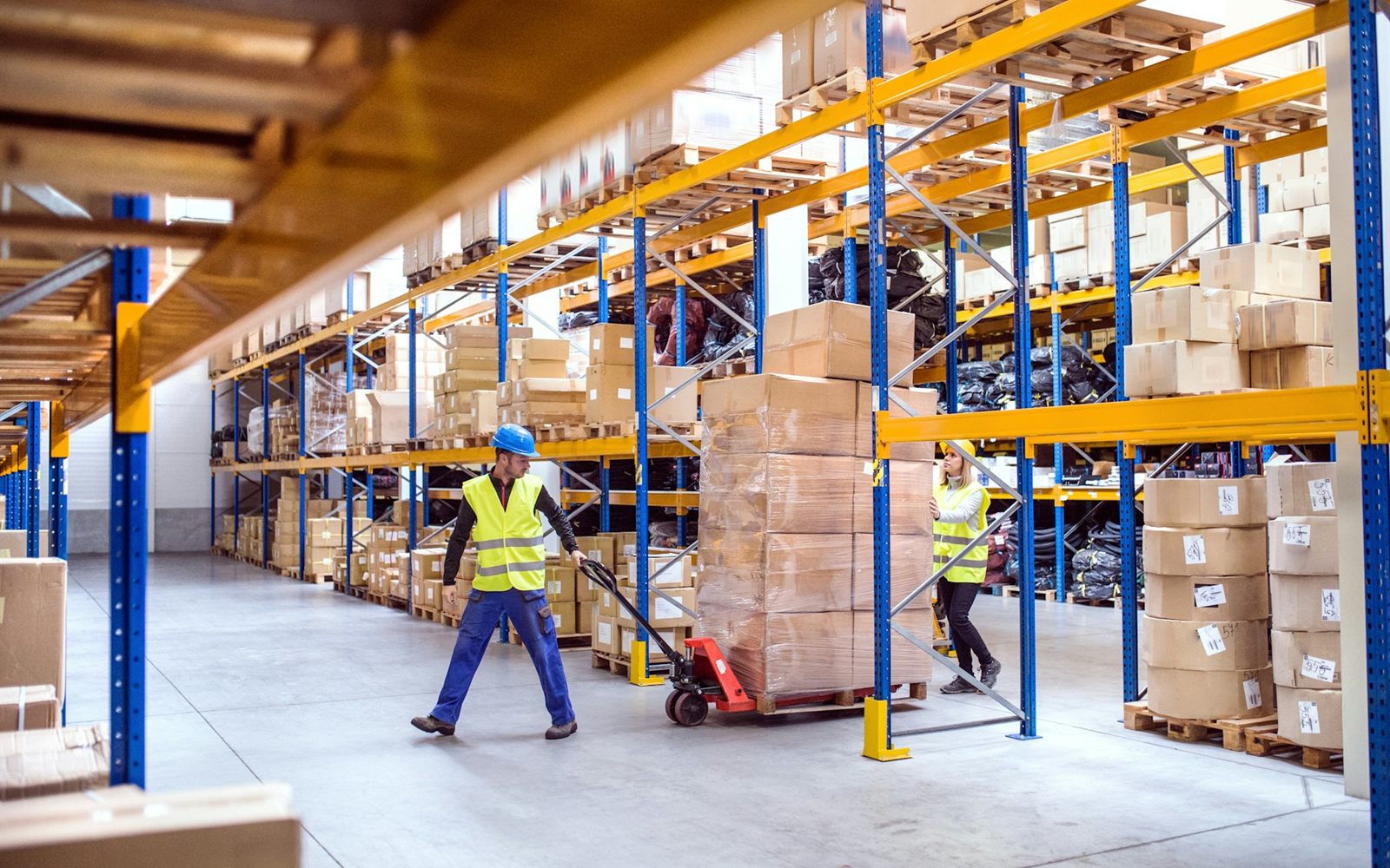 Trabajadores moviendo pallets en un almacén industrial