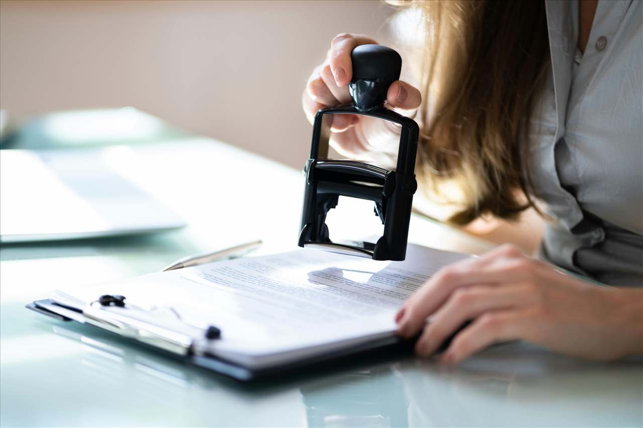 Persona revisando un documento de certificación sobre una mesa de trabajo